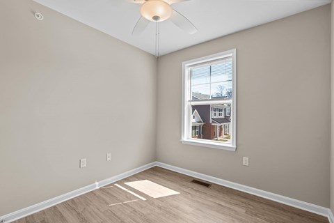 A room with a window and a picture of a house on the wall.