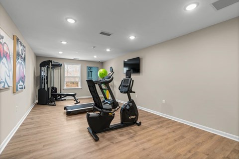 A spacious gym with a treadmill, elliptical trainer, and a stationary bike.