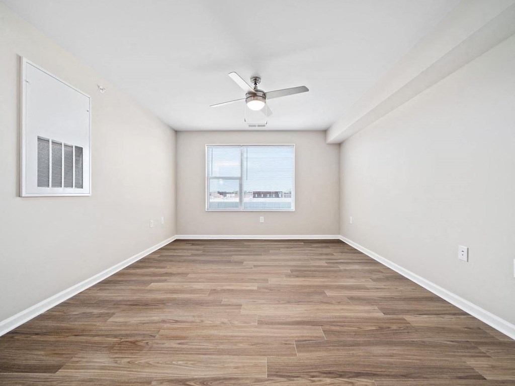 an empty living room with a ceiling fan and a window