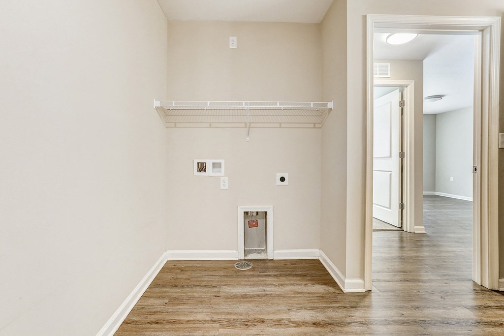 an empty living room with a wood floor and white walls