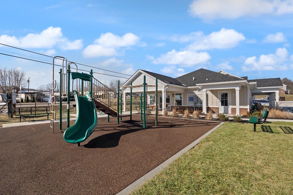 A playground with a green slide and a brown ground.