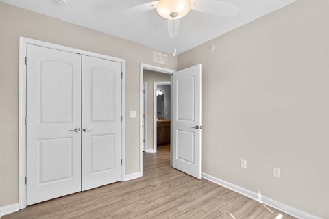 A room with a white door and a ceiling fan.