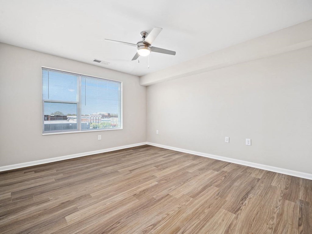 an empty living room with a ceiling fan and a window