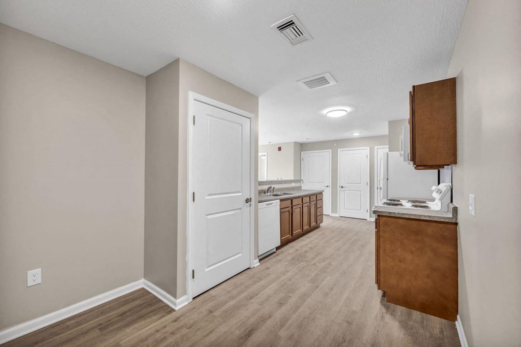 a renovated kitchen and living room with white walls and wood floors