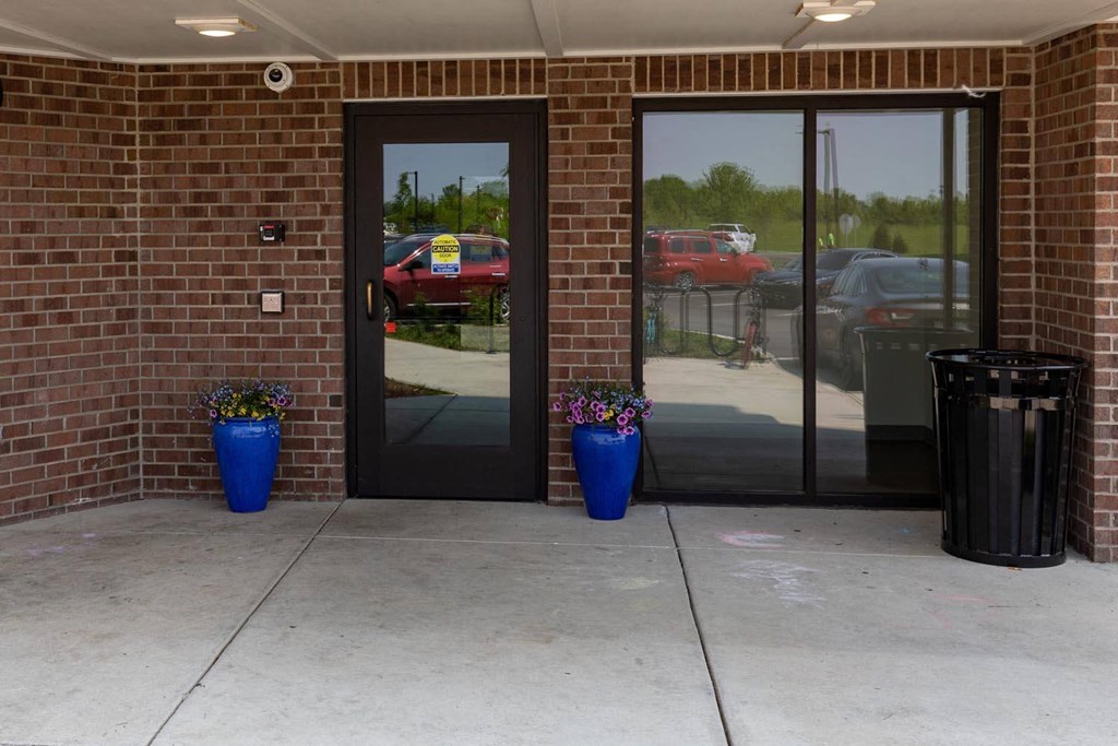 a building with two doors and two blue planters with purple flowers