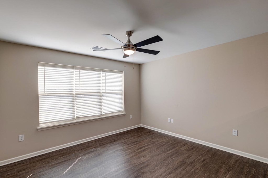 a bedroom with a large window and a ceiling fan