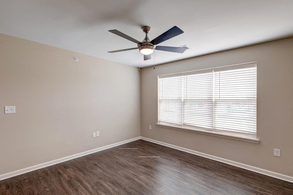 a bedroom with a large window and a ceiling fan