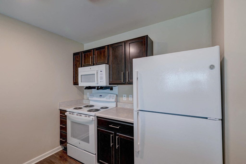a kitchen with white appliances and dark wood cabinets