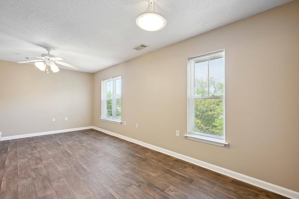 an empty living room with a ceiling fan and a window