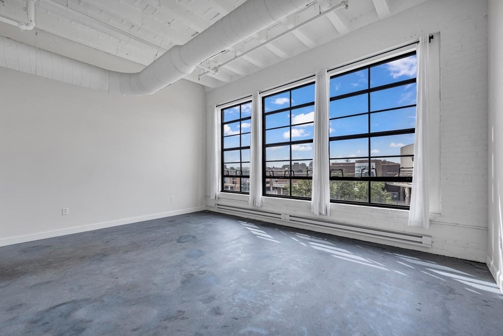 an empty room with large windows and a concrete floor