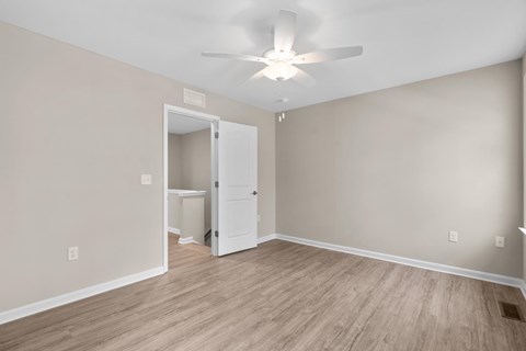 A room with a ceiling fan and a door leading to another room.