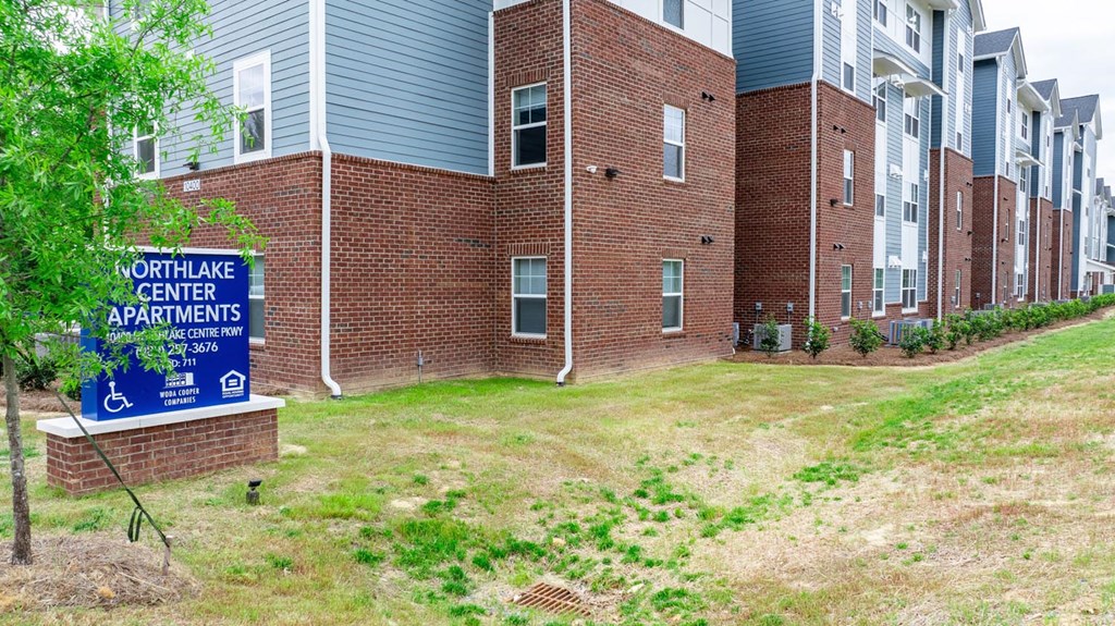 an apartment building with a sign in front of it