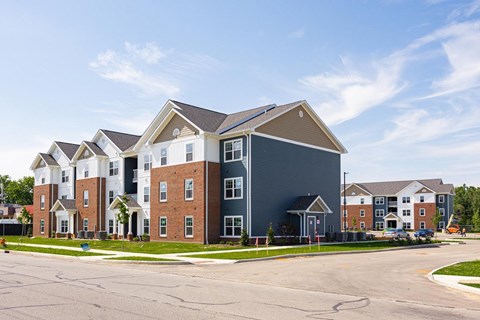 A large multi-story residential building with a parking lot in front.