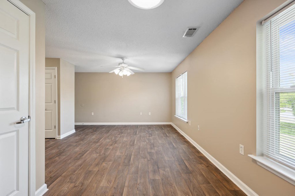 an empty living room with wood floors and a ceiling fan