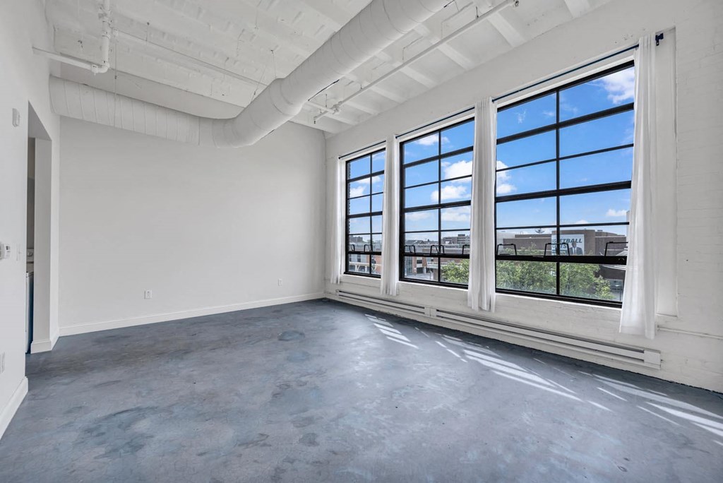 an empty room with large windows and a concrete floor