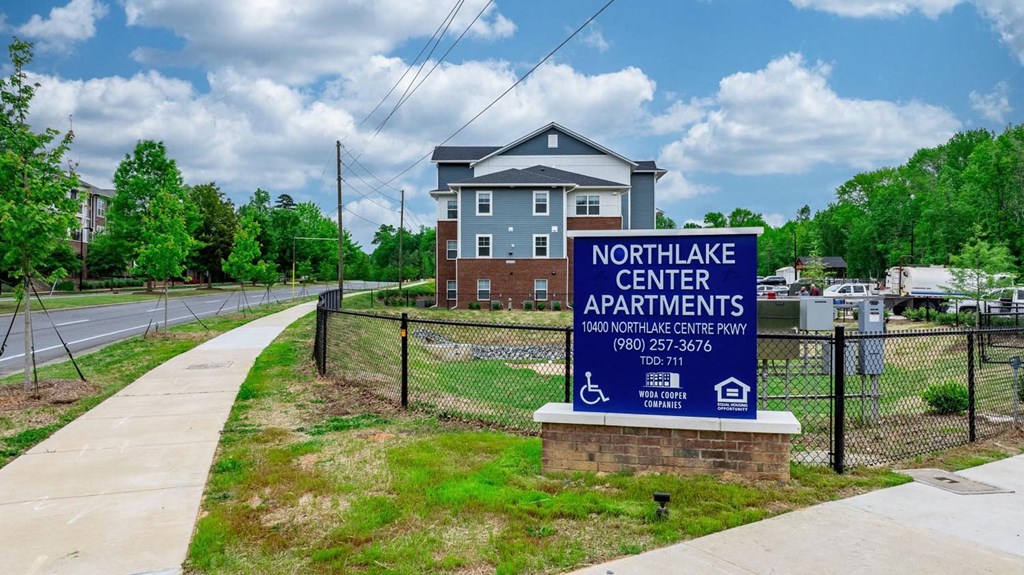 the entrance to the northwest center apartments sign in front of a fence