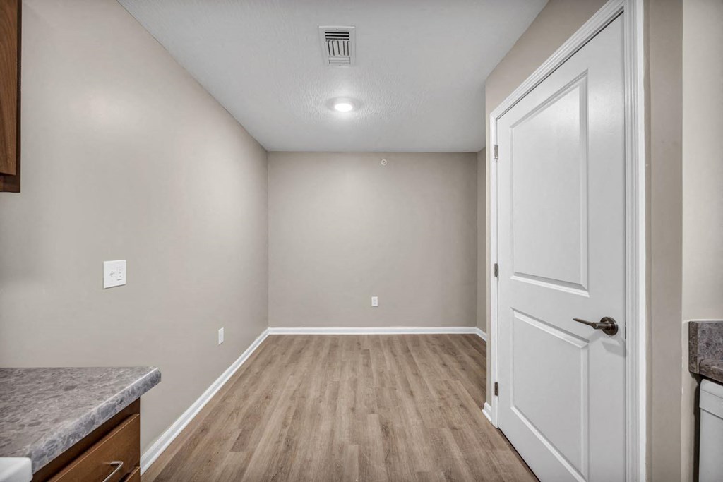the kitchen and living room of a new home with white walls and wood flooring