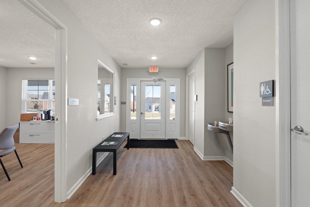 A hallway with a black bench and a black mat on the floor.