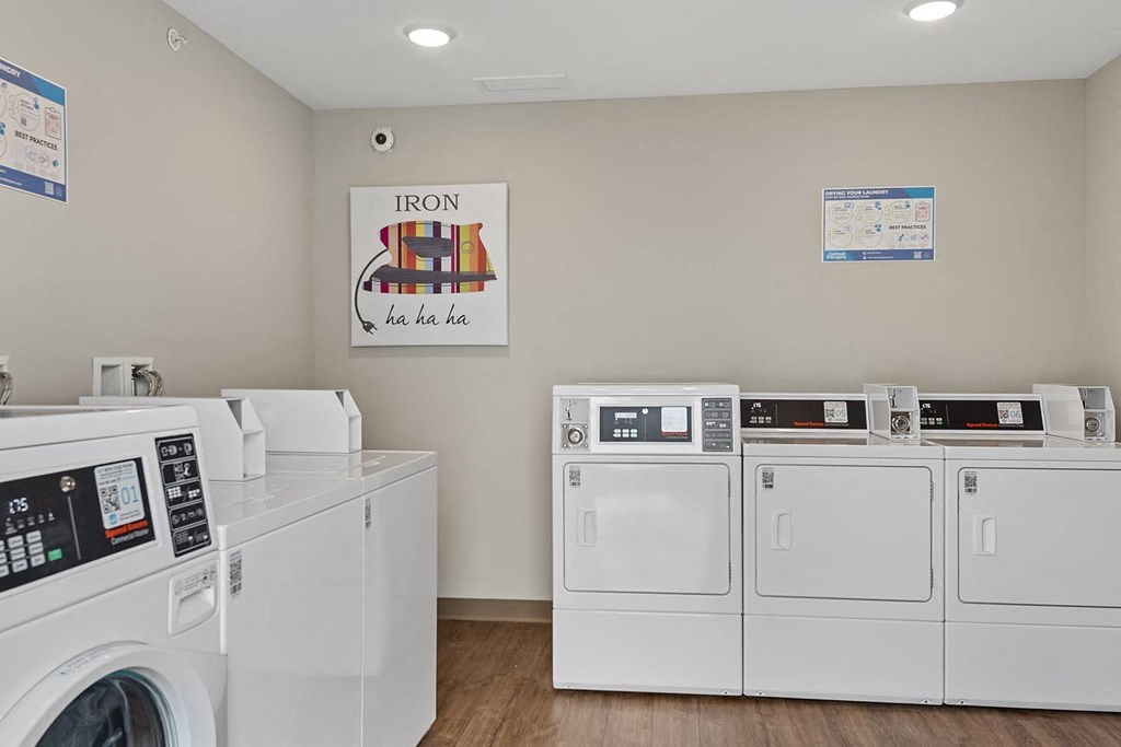a laundry room with washes and dryers and a poster on the wall