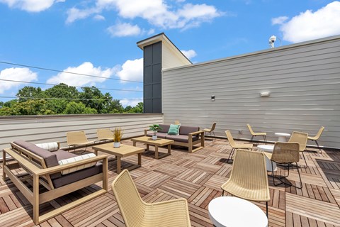 A wooden deck with chairs and tables is set up on a sunny day.