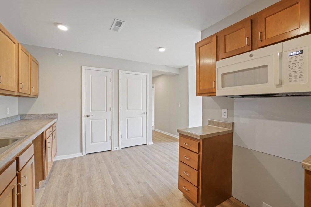 an empty kitchen with wooden cabinets and a microwave