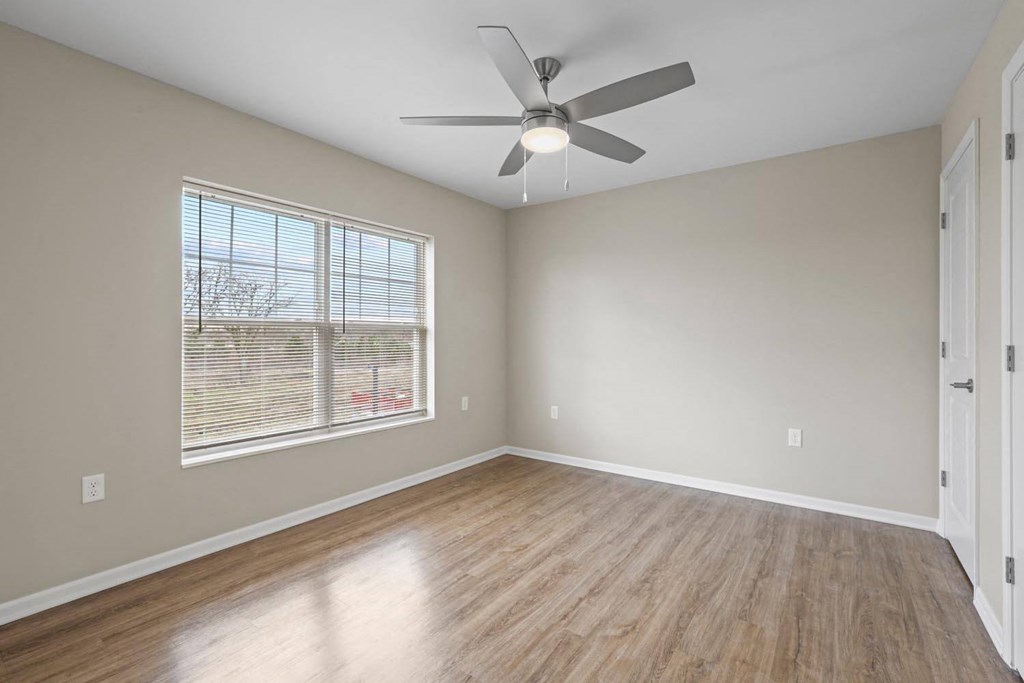 an empty living room with a ceiling fan and a window