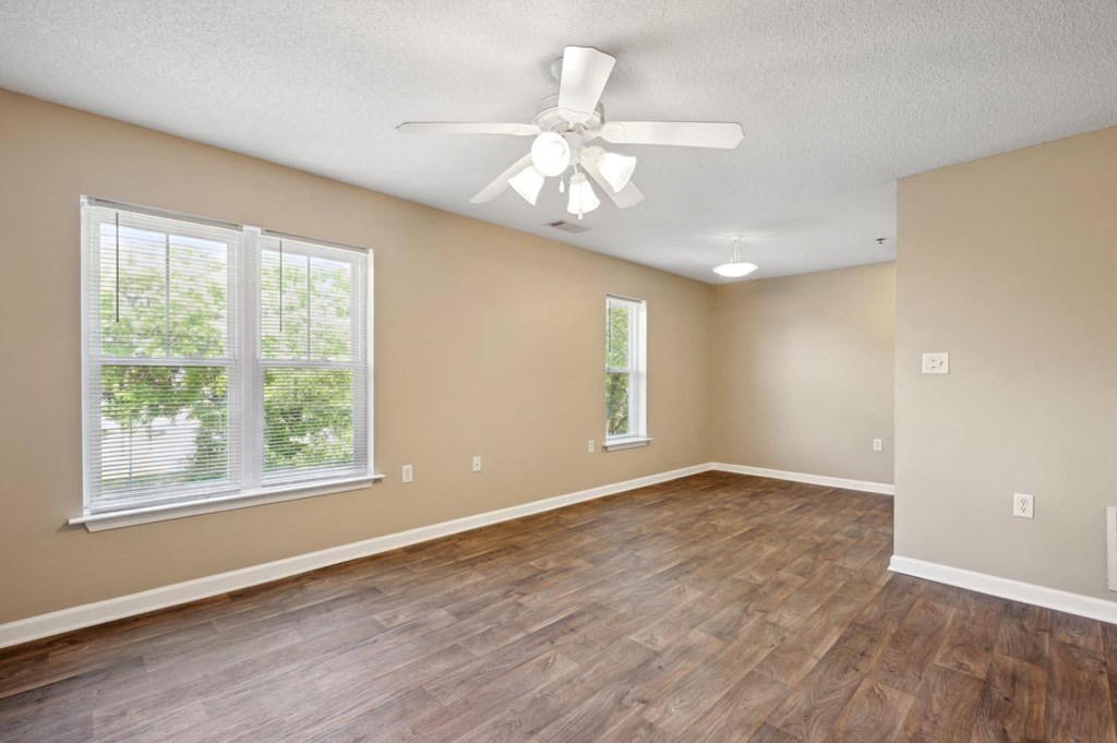 an empty living room with a ceiling fan and a window