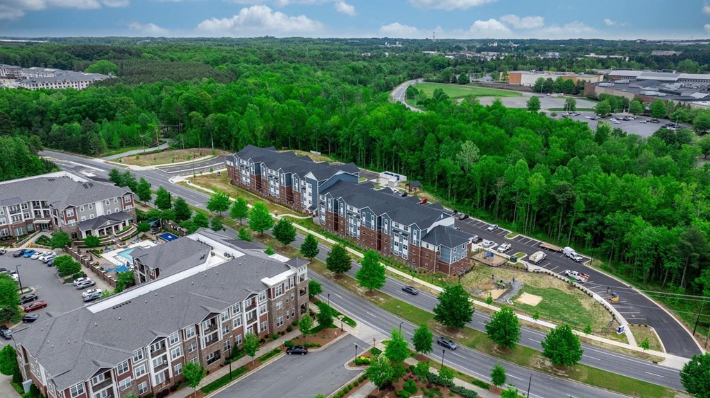 an aerial view of an apartment complex with a highway and trees