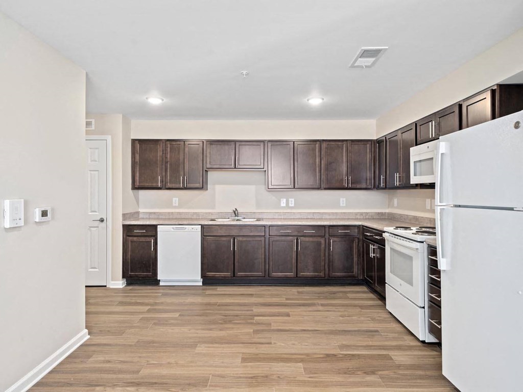 a kitchen with white appliances and dark wood cabinets