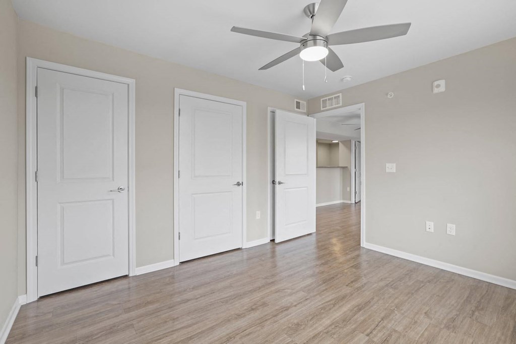 an empty living room with white doors and a ceiling fan