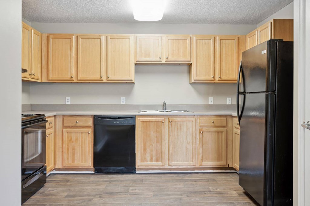 a kitchen with wooden cabinets and a black refrigerator