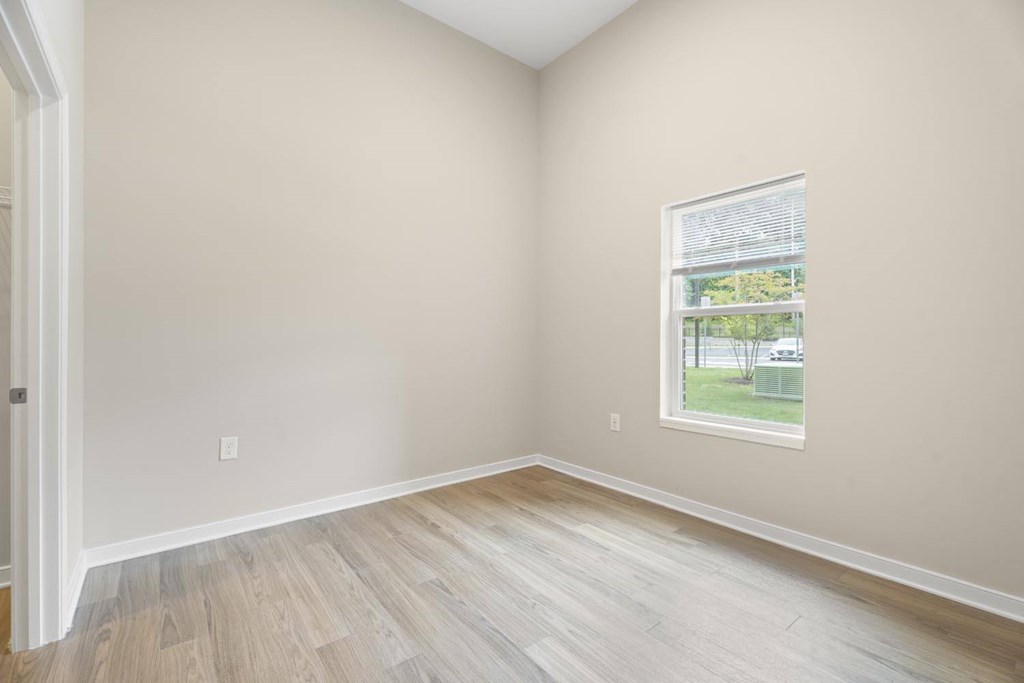 A room with a window and wooden flooring.