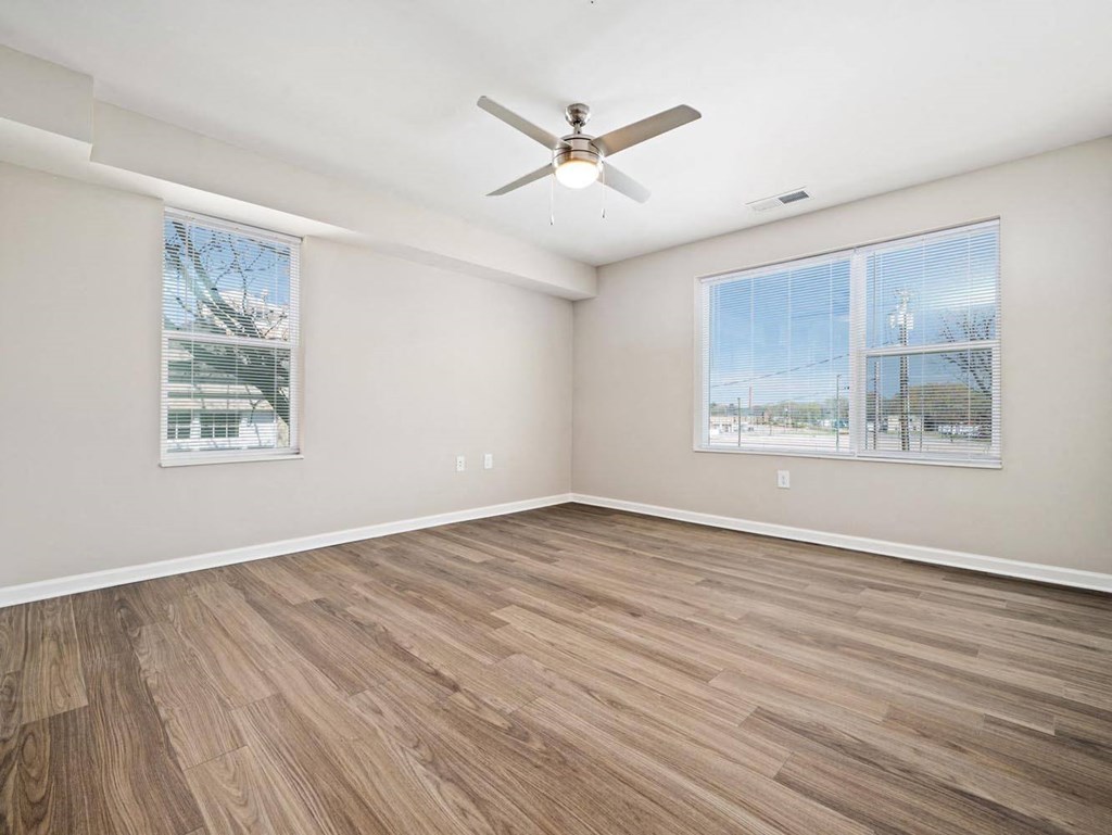 an empty living room with a ceiling fan and a window