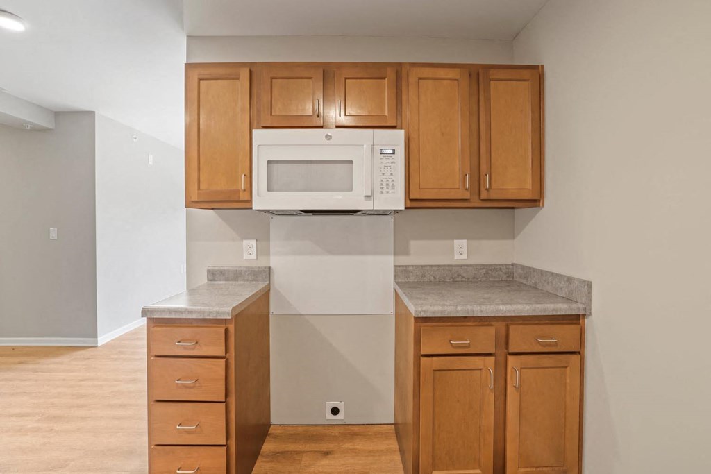 a kitchen with a white microwave and wooden cabinets