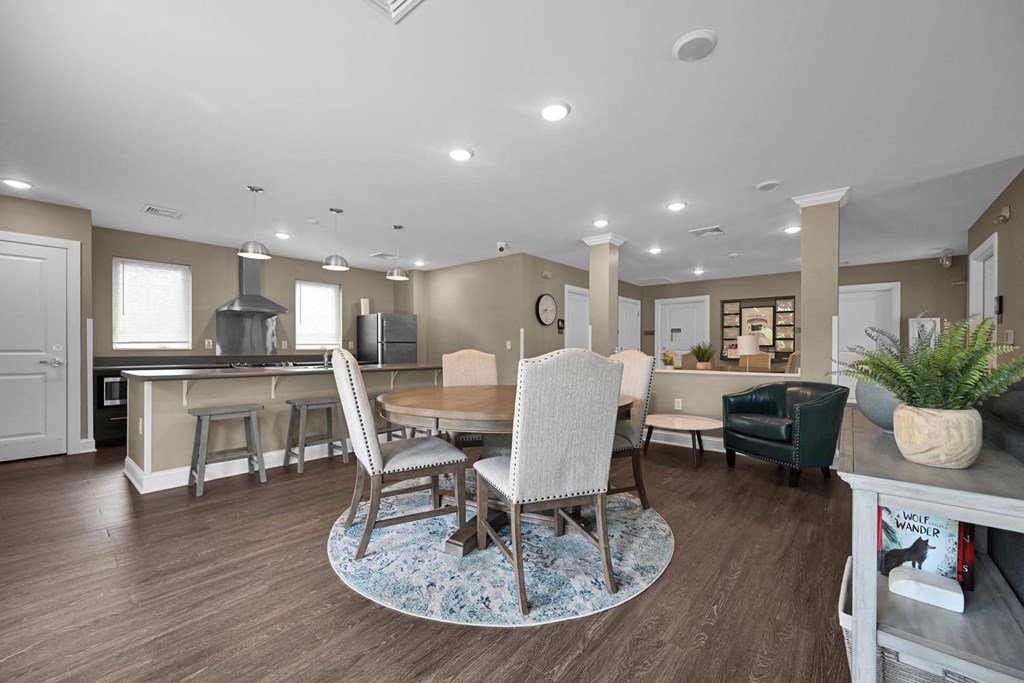 a living room with a table and chairs and a kitchen in the background