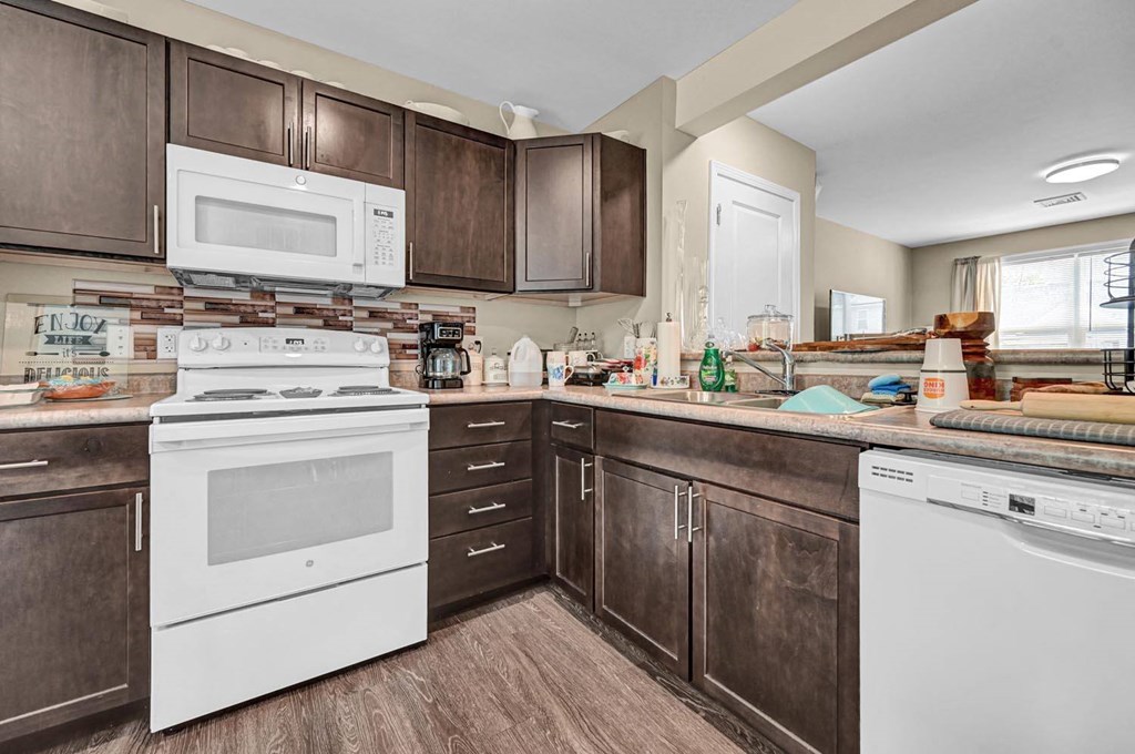 a kitchen with dark wood cabinets and white appliances