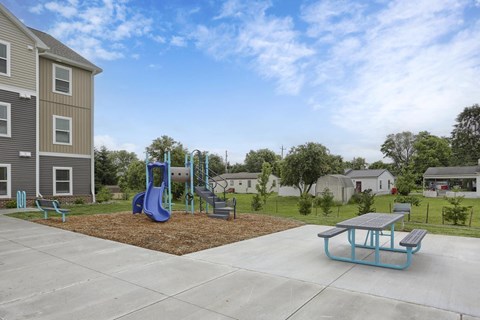 A playground with a blue slide and a picnic table.