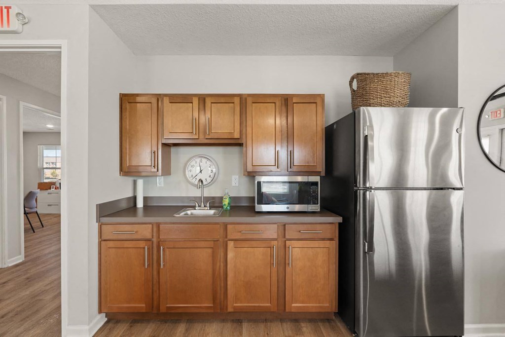 A kitchen with wooden cabinets and a stainless steel refrigerator.