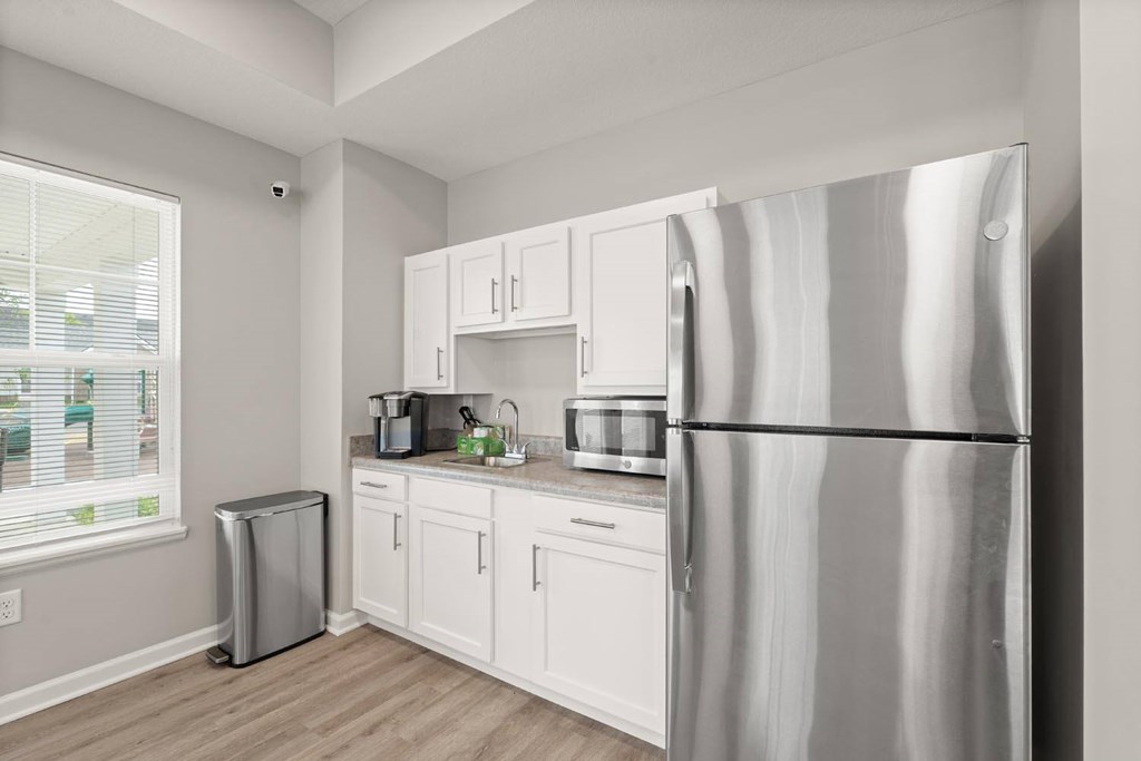 A kitchen with white cabinets and a stainless steel refrigerator.