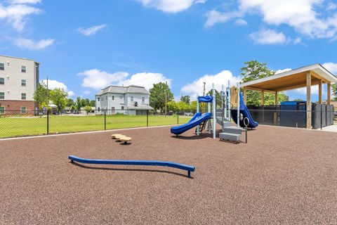 A playground with a slide, seesaw, and a ball.