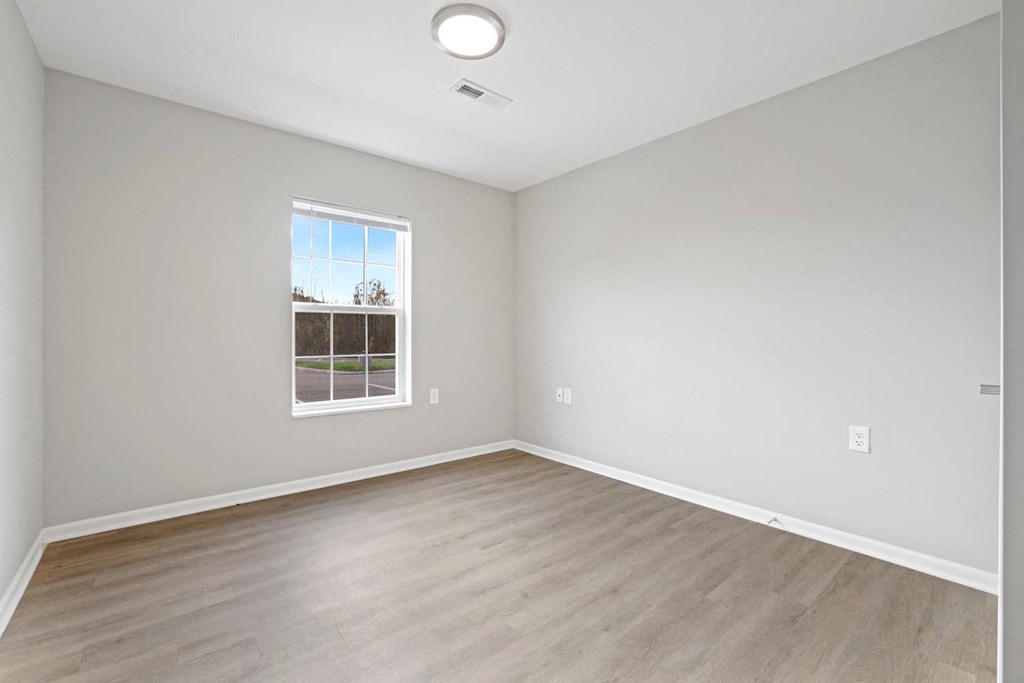 an empty room with a window and wood floors