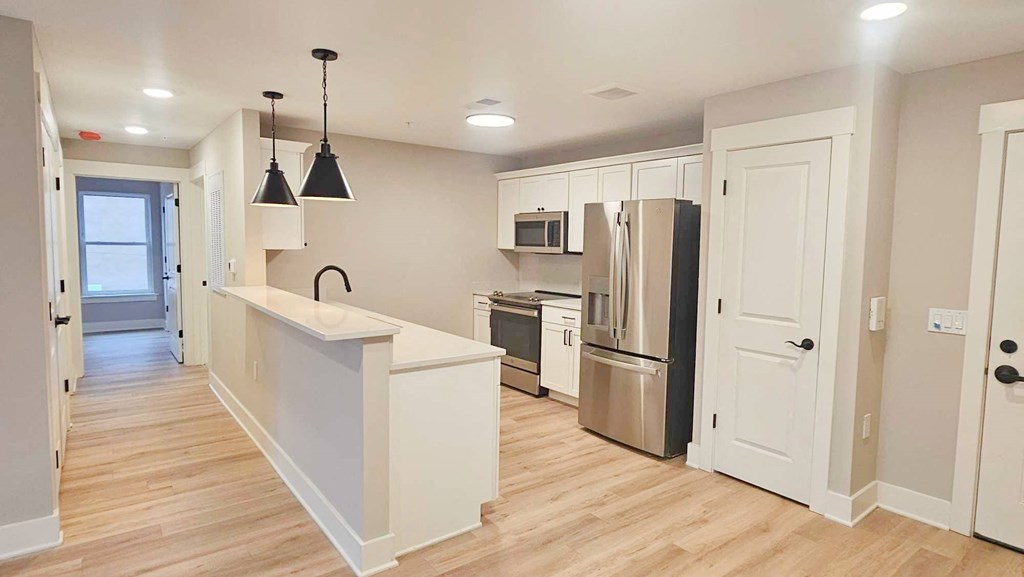 an open kitchen with a large island and a stainless steel refrigerator
