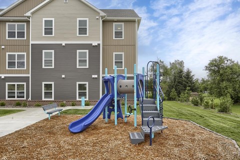 A playground with a blue slide and a grey and blue slide.
