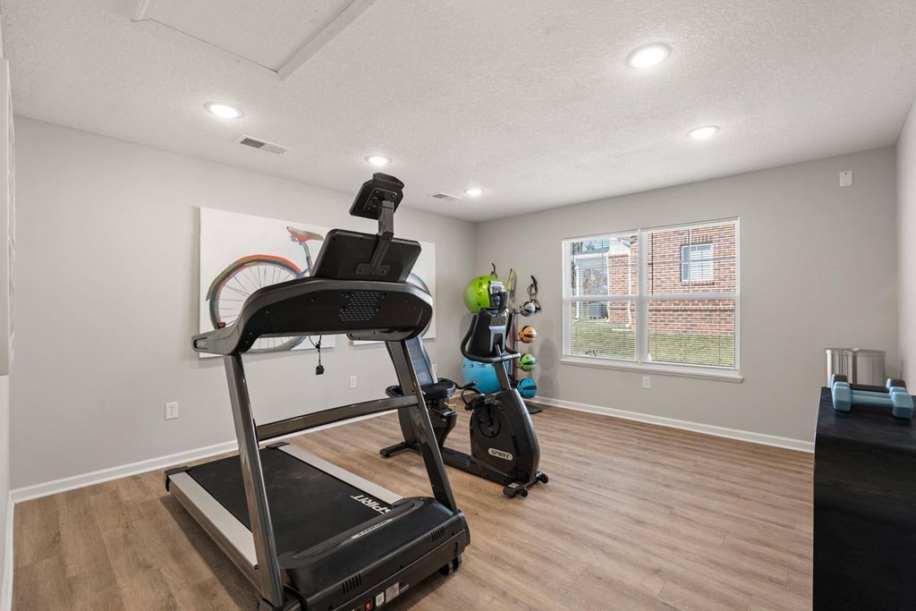 A treadmill with a tablet on top is in a room with a window.