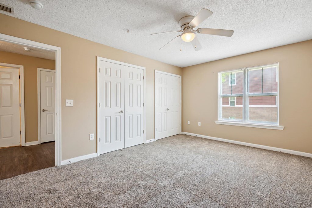 an empty living room with a ceiling fan and a window