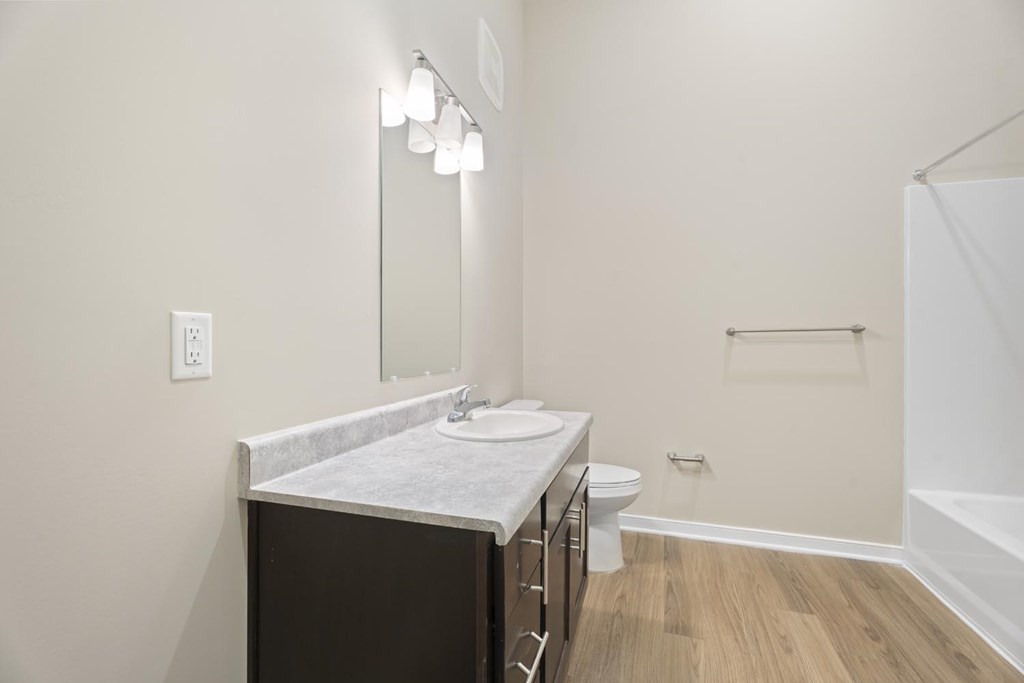 A bathroom with a sink, mirror, toilet, and bathtub.