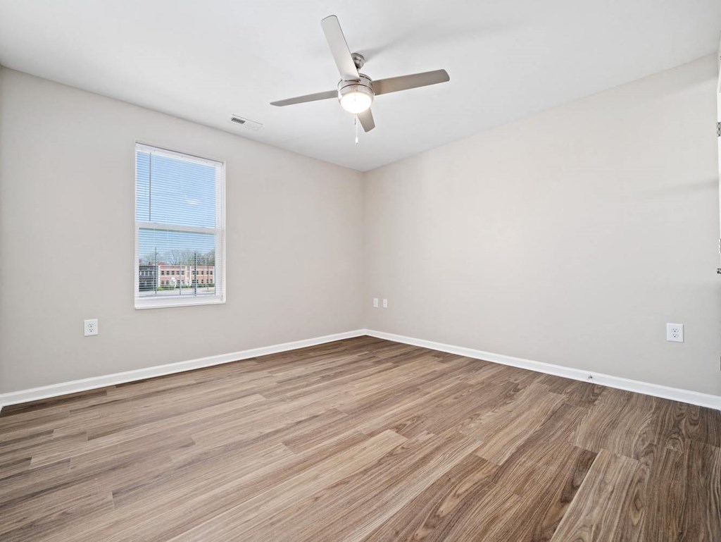 an empty living room with wood floors and a ceiling fan