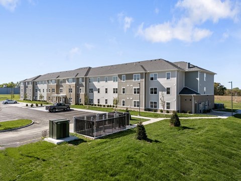 an exterior view of an apartment building with a parking lot