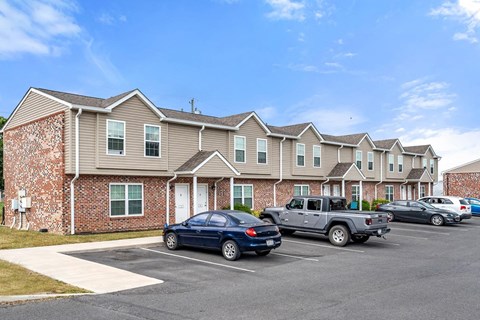 a parking lot in front of an apartment building with cars parked in front