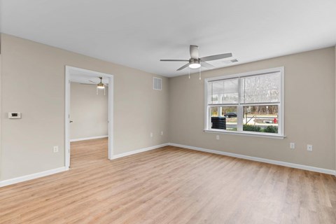 A room with a ceiling fan and a window with a view of the outside.